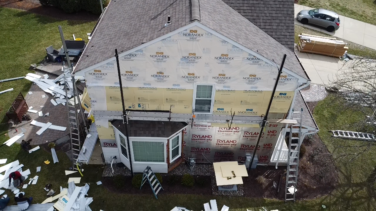 Aerial view of a Gambrills MD home with siding removed and Norandex house wrap exposed during Prime Roofing & Siding install